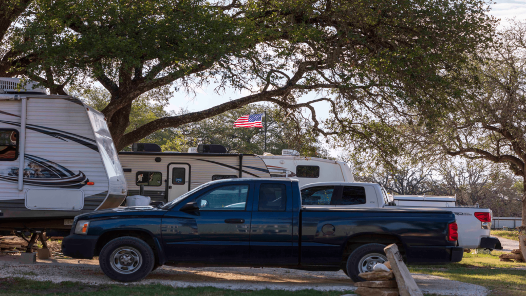 a truck parked next to a camper and an American flag is showing in the background