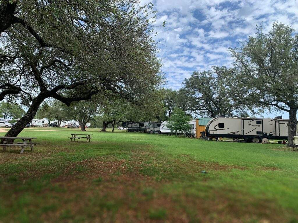 An aerial view of multiple RVs parked in an Rv park scenic, rural setting with picnic benches